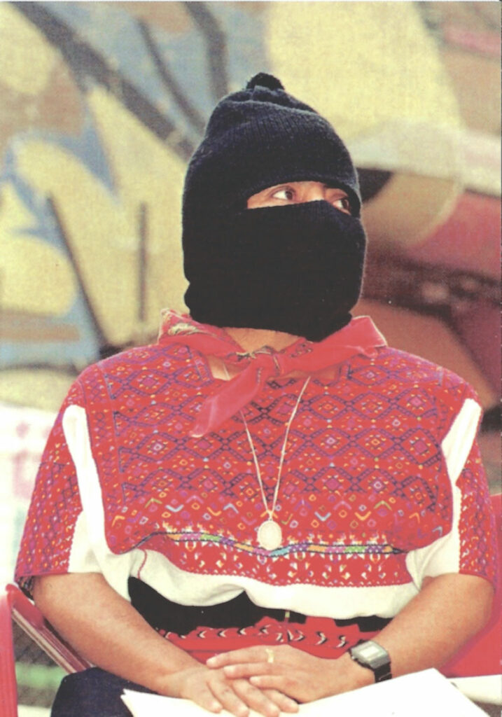 En bild som visar en person med röda kläder och svart huva som täcker huvudet. 