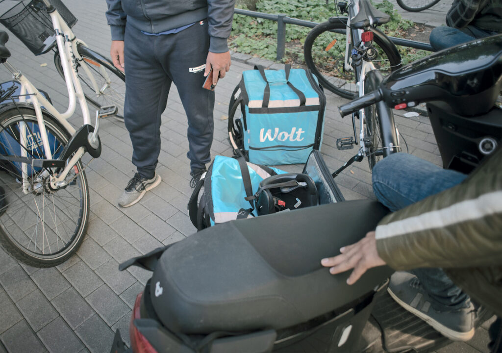 En samling cyklar och väskor att bära mat i som ska levereras till kunder med hjölp av cykel eller moped. Från utställningen "gig-personen bakom appen" på Arbetets museum i Norrköping. "En win-win situation" är rubriken för recensionen.
