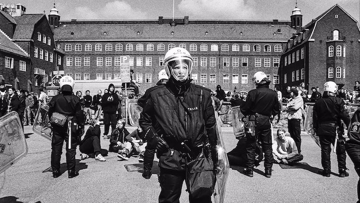 Kravallutrustade poliser. I bakgrunden syns andra människor samt Hvitfeldtska skolan i Göteborg.