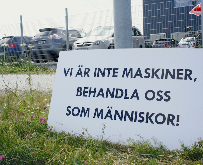 Plakat med texten "Vi är inte maskiner, behandla oss som människor". Utanför Zalandos lager. 