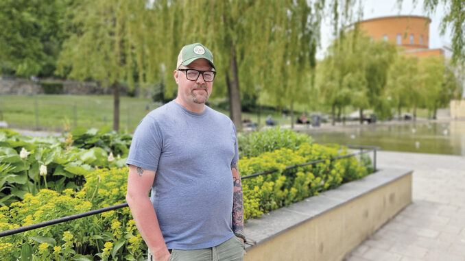 Marcus Vildir står i en park på Sveavägen i Stockholm. Stadsbiblioteket syns i bakgrunden.