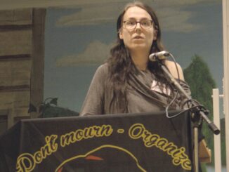 Abby Hillbom står i en talarstol på SAC Syndikalisternas kongress 2025