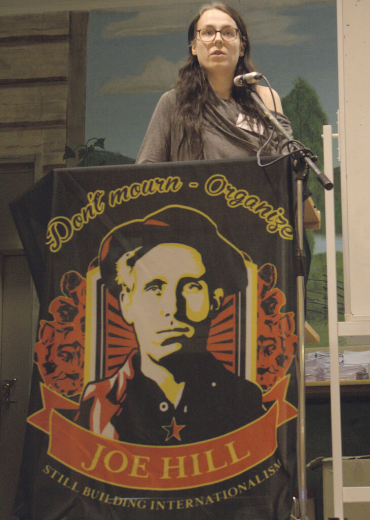 Abby Hillbom står i en talarstol på SAC Syndikalisternas kongress 2025