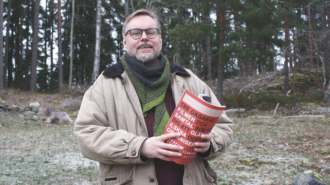 SAC:s nye informationsorganisatör och redaktör för Syndikalisten står i ett senhöstlandskap och håller ett nummer av Syndikalisten i handen.